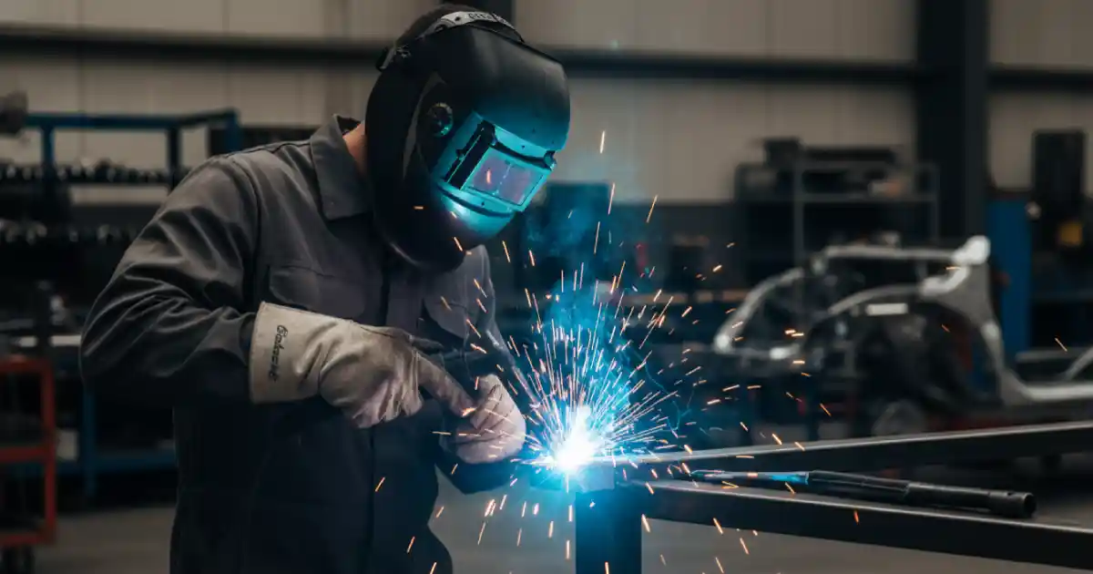 Saldatore professionista esegue saldatura MIG su componente metallico in officina automotive